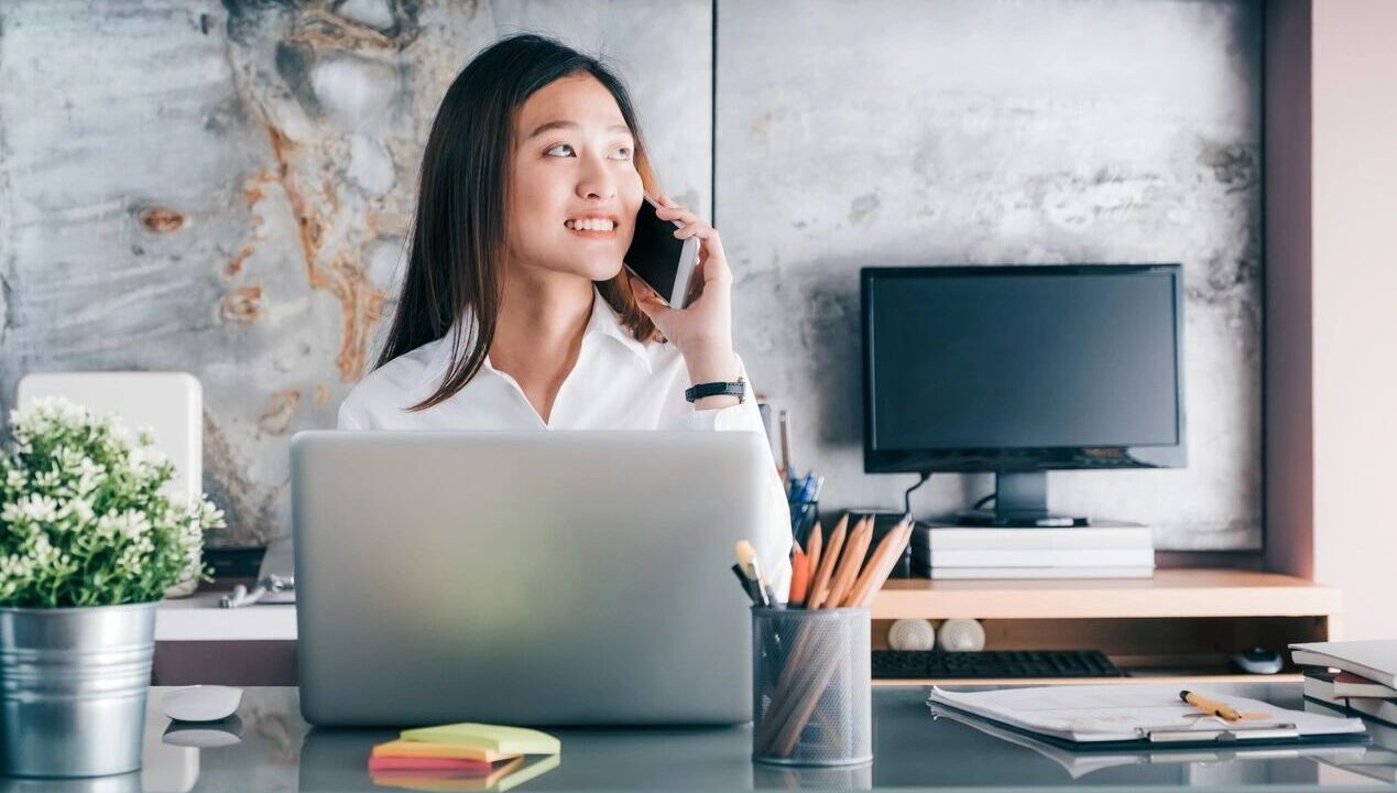 Woman on phone at modern office desk.